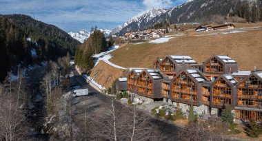 Dolomitler, İtalya 'da dağ evi tarzı binaları olan Alp Oteli. Karlı tepeler, yemyeşil ormanlar, ve akarsu kaplı bir yol sakin bir kış manzarası yaratır..