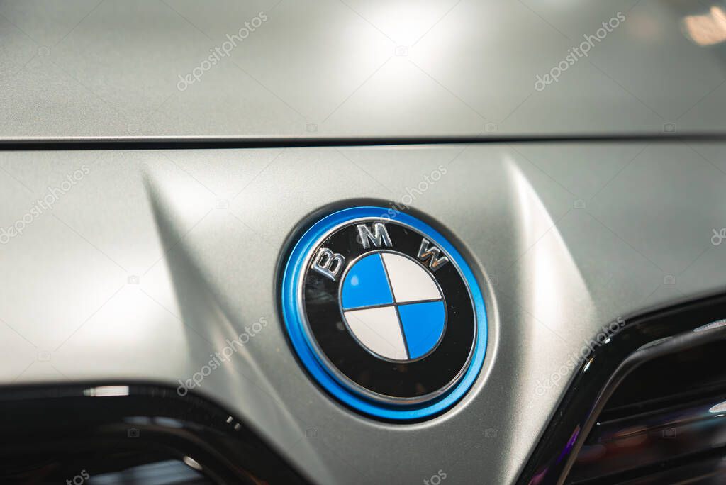 The iconic BMW logo with blue and white quadrants is displayed on the hood of a silver car, reflecting light at the BMW Museum in Munich.