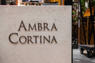 Cortina, Dolomites, İtalya 'da bir butik otelde yükseltilmiş harfli mermer masa, kitaplar, çam kozalağı ve sıcak aydınlatma.