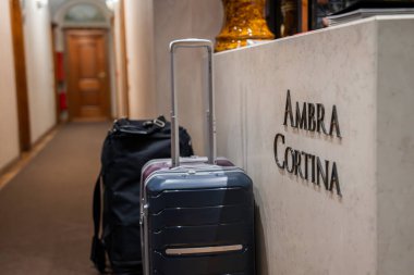 Mermer masası, modern bavulu, ahşap kapısı, kemerli kapısı ve Cortina, Dolomites, İtalya 'daki Ambra Cortina' da altın vazosu olan resepsiyon alanı..