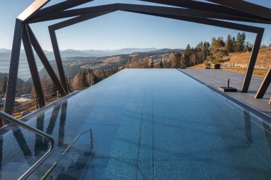 İtalya, Güney Tyrol 'daki yuvarlanan tepelere, dağınık ağaçlara ve sıradağlara karşı açısal metal kirişlerle çerçevelenmiş lüks sonsuzluk havuzu..