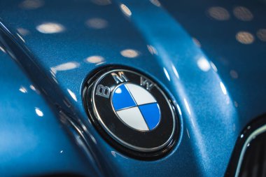 BMW logosunu metalik kaputu olan mavi bir arabanın kaputuna kapatın, dairesel ışıkları yansıtıyor. Almanya 'nın Münih kentindeki BMW Müzesinde yakalandı..