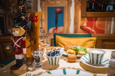 Kahvaltı malzemeleri, şenlikli bir dekor, fındıkkıran, küçük bir Noel ağacı ve butik bir otel ortamında canlı bir sanat eseri olan rahat bir yemek masası..