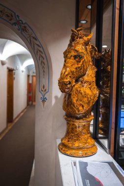 Cortina, Dolomites, İtalya 'daki butik otelin içinde pencere pervazında parlak turuncu bir at kafası heykeli, kemerli kapı aralığı ve ahşap koridor bulunuyor..