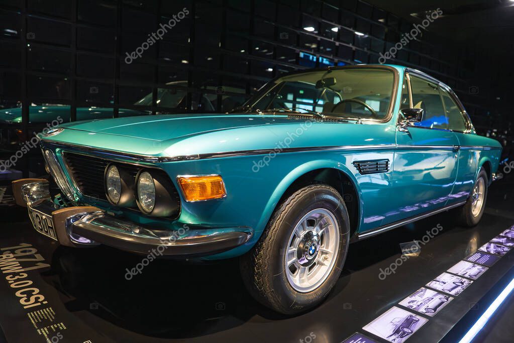 A turquoise BMW 3.0 CSI coupe with chrome accents, dual headlights, and kidney grille on an illuminated platform at the BMW Museum in Munich, Germany.