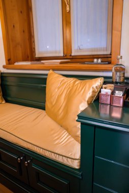 Altın yastıklı yeşil bank, ahşap çerçeveli pencere ve Cortina, Dolomitler, İtalya 'da butik bir otelde su ve çay paketleri bulunan masa..