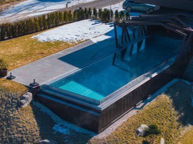 Güney Tyrol, İtalya 'da modern bir otelde pergola ile gösterişli bir açık havuz. Kar, yeşillik ve kışın görülebilen bir yol..