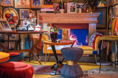 İçinde taş bir şömine, renkli mobilyalar, çerçeveli sanat eserleri ve Cortina, Dolomitler, İtalya 'da dekoratif eşyalar bulunan canlı bir otel içi..