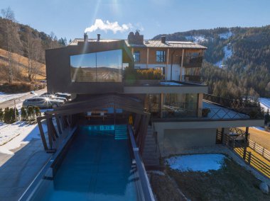 İtalya 'nın South Tyrol şehrinde cam camları, ahşap aksanları, açık havuzu, karla kaplı tepeleri ve sık ormanları olan lüks bir otel..