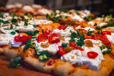 Taze pişmiş, altın hamurlu pizza, vişneli domates, kremalı peynir, yeşiller ve zeytinler, İtalya 'nın Bergamo, İtalya' daki mutfak geleneklerini yansıtıyor..