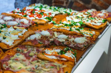 Bergamo, İtalya 'da kırsal tuğla bir duvara karşı döşenmiş mozzarella, et ve sebze gibi çeşitli malzemelerle yeni hazırlanmış pizzalar..