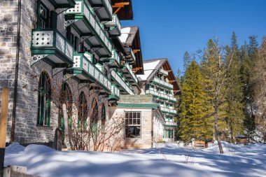 Yeşil ve beyaz balkonları, kemerli pencereleri ve Braies Gölü yakınlarında karla çevrili dik çatısı olan büyüleyici dağlık bir bina..