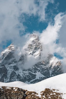 İkonik Matterhorn, kar kaplı yamaçlar ve İsviçre 'nin Zermatt kenti yakınlarındaki kayalık arazisiyle parlak mavi bir gökyüzüne sert bir şekilde yükselir..