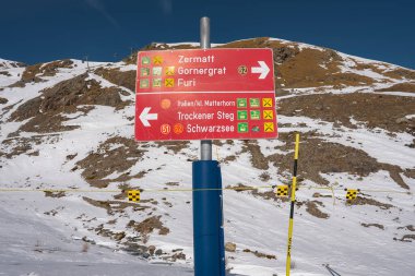 Zermatt, Gornergrat ve Klein Matterhorn gibi kayak rotaları olan kırmızı işaret direği karlı bir dağlık alana ve açık mavi gökyüzüne karşı kurulmuştur..