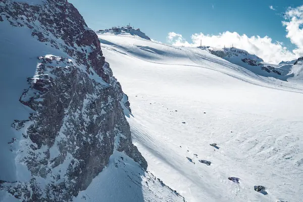 İsviçre, Zermatt 'ta kayak pisti ve kayak pistleri karla kaplıydı. Zirvenin tepesinde bir yapı ve açık mavi bir gökyüzü kış sahnesini tamamlıyor..