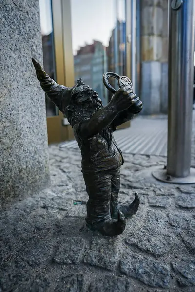 Polonya, Wroclaw 'da cam kapıların yanındaki kaldırımda çubuk kraker bulunan bronz bir cüce heykeli. Sivri uçlu şapka ve kıvrık ayakkabılar..