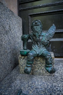 Polonya 'nın Wroclaw kentindeki bir granit blokta elinde kalem ve mürekkep şişesiyle küçük bir bronz cüce heykeli bulunuyor..