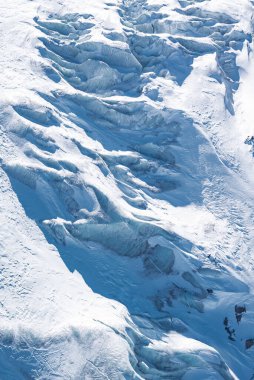 İsviçre 'nin Zermatt kentindeki bir buzulun hava görüntüsü, buzlu yarıklar, dalgalı oluşumlar ve koyu mavi ve beyaz renklerin karışımı..