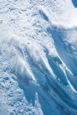 Zermatt, İsviçre veya Cervinia, İtalya yakınlarındaki bir buzulun ayrıntılı görüntüsü, karmaşık buz oluşumları, yarıklar ve engebeli kar örtülü arazileri gösteriyor..