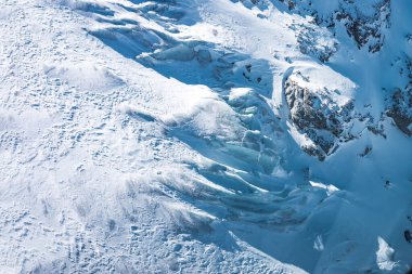 İsviçre 'nin Zermatt kentindeki bir buzulun, yarıkların, kayalık çıkıntıların ve kar ve buz kalıplarını vurgulayan doğal ışığın hava görüntüsü.