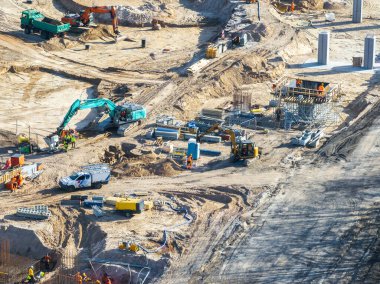 Yüksek görüş mesafesi olan işçiler, Letonya Riga 'daki bir inşaat sahasında vinçleri, iskelesi ve beton sütunları olan makineler kullanıyorlar..