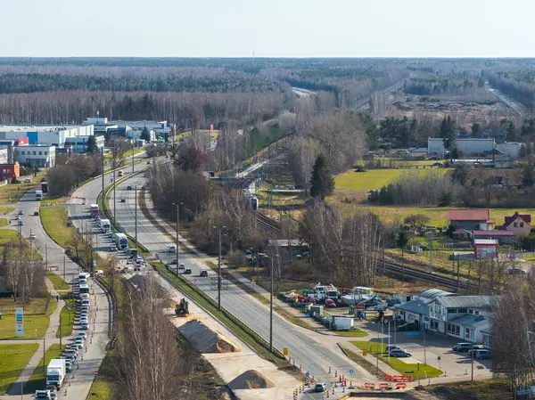 Riga, Letonya 'daki inşaat alanı kısmen tamamlanmış bir yol, ekipman, trafik, yakındaki binalar, açık alanlar ve ormanlık bir arka plan gösteriyor..