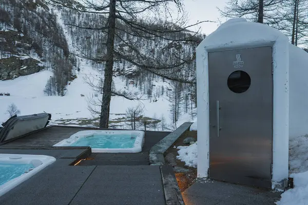 Zermatt, İsviçre 'de iki dumanı tüten jakuzi, karla kaplı buhar odası ve karlı yamaçlar ve seyrek ağaçlarla dolu bir kaplıca alanı..
