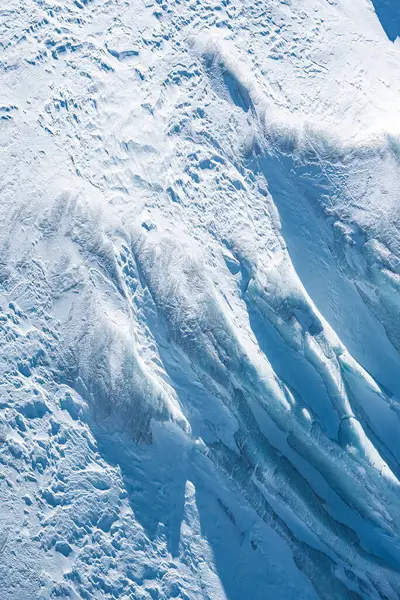 Zermatt, İsviçre veya Cervinia, İtalya yakınlarındaki bir buzulun ayrıntılı görüntüsü, karmaşık buz oluşumları, yarıklar ve engebeli kar örtülü arazileri gösteriyor..