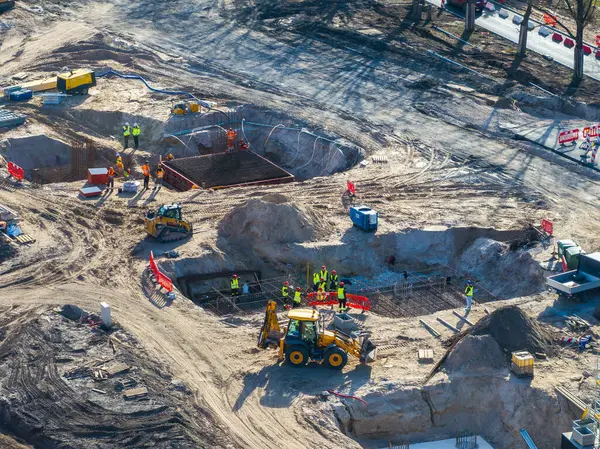 Riga, Letonya 'daki inşaat sahasında işçiler, kazıcılar, yükleyiciler, güvenlik bariyerleri ve karayolu ve köprü altyapı geliştirme materyalleri yer alıyor..