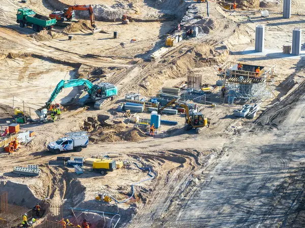 Yüksek görüş mesafesi olan işçiler, Letonya Riga 'daki bir inşaat sahasında vinçleri, iskelesi ve beton sütunları olan makineler kullanıyorlar..