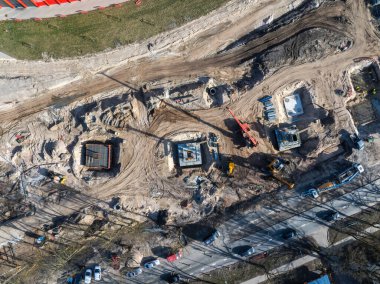 Riga, Letonya 'daki bir inşaat alanının hava görüntüsü vinçleri, kazıcıları, beton temelleri, eğri toprak bir yol ve yakınlardaki kırmızı bir binayı gösteriyor..