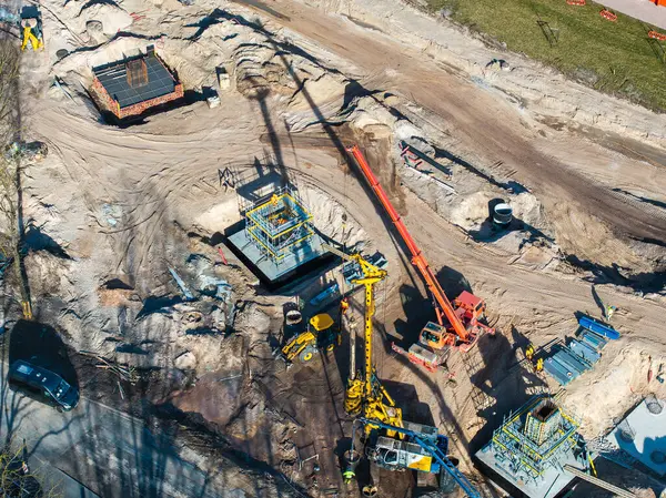 Riga, Letonya 'daki inşaat sahasında vinçler, kazıcılar, işçiler, çelik iskeletler, beton yapılar ve erken gelişimde dağınık malzemeler görülüyor..