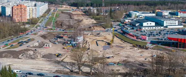 Riga, Letonya 'da büyük bir inşaat alanı, ağır makineler, inşaat halindeki bir döner kavşak, kentsel binalar, ve orman geçmişi.