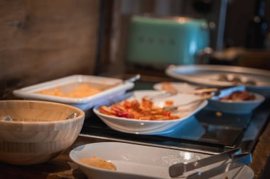 Dilimlenmiş meyveler, kremalı bir tabak ve sıcak Alp ayarı içindeki ahşap elementlerle birlikte nane yeşili bir tost makinesinin yer aldığı kahvaltı setini kapatın..