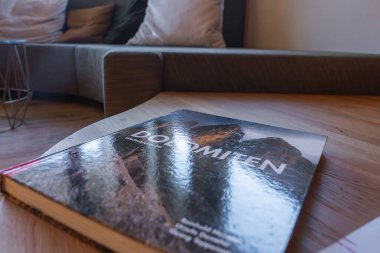 İçinde Dolomitler 'in kitabı olan ahşap bir masa, yastıklı modern bir kanepe ve İtalya' nın South Tyrol kentindeki lüks bir otelde hafif ışıklandırma var..