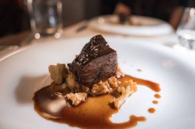 Lüks bir Alp otelinde beyaz bir tabağa kahverengi sos serpiştirilmiş, parçalanmış ekmek ya da tahıllar üzerinde pişirilmiş yumuşak, jöleli et..