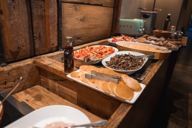 Kahvaltı büfesi krep, hamur işi, sotelenmiş mantar ve ahşap tezgahta daha fazlası. Arka planda bir nane yeşili tost makinesi ve kahve makinesi var..