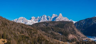 Tırtıklı Dolomite dağları, karlı zirveleri, sık yeşil ormanları, küçük bir yerleşim yeri, ve İtalya 'nın Güney Tyrol şehrinde kısmen donmuş bir göl.