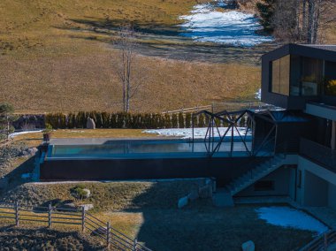 Güney Tyrol, İtalya 'da çağdaş bir otelde yansıtıcı yüzeyi olan parlak bir sonsuzluk havuzu çimenli tarlalar, kar bantları ve yuvarlanan tepelerle çevrili..
