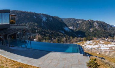 Güney Tyrol, İtalya 'da lüks bir otel, sonsuz bir havuz, fayanslı veranda, kar tozlu dağlara ve açık alanlara karşı çağdaş tasarım.