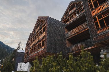 İtalyan Alpleri 'nde ahşap mimari, birden fazla balkon ve eğimli çatılarla çevrili, yeşil ağaçlar ve dağlarla çevrili lüks bir otel..