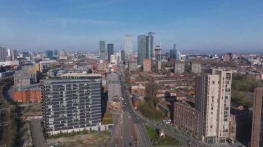 Manchester, İngiltere 'nin hava görüntüsü, açık mavi gökyüzü altında Beetham Kulesi, gökdelenler, tren yolları ve inşaat vinçlerini gösteriyor..