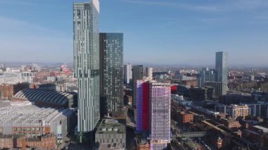 Manchester, İngiltere 'nin havadan görünüşü, Beetham Tower gibi gökdelenler, inşaat halindeki kırmızı ve beyaz bir bina, tren rayları ve hareket halindeki bir tren..