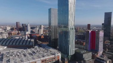 Manchester, İngiltere 'nin hava görüntüsü Deansgate Meydanı kulelerini modern gökdelenleri, tren raylarını ve açık gökyüzünün altında kırmızı ve mavi bir binayı gösteriyor..