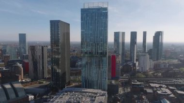 Manchester, İngiltere 'nin havadan görünüşü, modern cam kuleler, hareket eden trenler, yollar, yeşillikler ve vinçler, şehirde geniş çaplı bir hareketle.