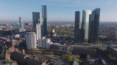 Manchester, İngiltere hava manzarası, Deansgate Meydanı, kırmızı tuğla binalar, tekneli bir kanal, yollar, yeşil alanlar ve açık mavi bir gökyüzü..