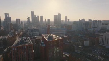 Manchester, İngiltere 'nin hava görüntüsü, modern gökdelenleri, tarihi mimariyi, inşaat vinçlerini ve pürüzsüz hareketli güneşli şehir manzarasını gösteriyor..
