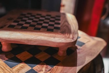 Siyah ve ahşap desenli iki sanatsal ahşap satranç tahtası. Ilık tonlar ve karmaşık işçilikle rafine edilmiş bir iç mekan..