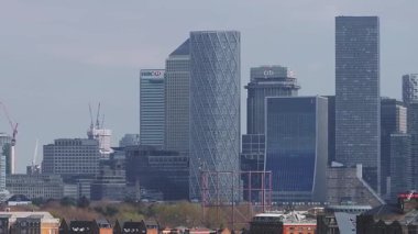 Londra 'nın Canary Wharf gökdelenlerinin, vinçlerin ve geleneksel binaların berrak mavi gökyüzü altında sergilendiği panoramik hava manzarası.