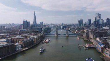 Thames Nehri 'ni kaplayan Kule Köprüsü' nün havadan görünüşü, arka planda Gherkin ve gökdelenler. Tekneler bulutlu bir gökyüzünün altında nehir boyunca hareket eder..